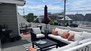 A deck with a white sofa, black armchair, and a small table. - Beautiful Raised Ranch with Views of the Bay (Surf City)