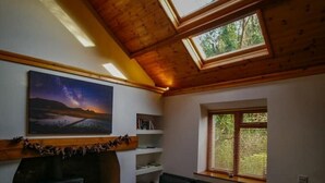 Ein gemütliches Wohnzimmer mit Kamin, einer schwarzen Ledersofa, einem Streifen Teppich und Dachfenstern.