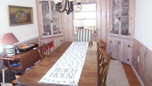 Een eetkamer met een houten tafel, stoelen, een kroonluchter en glazen vitrines langs de muur.