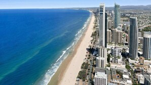 Un paysage urbain côtier avec de hauts immeubles, une plage et un ciel bleu dégagé.