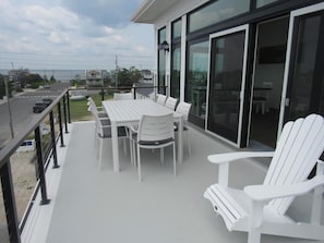 Un balcon avec une table et des chaises, une porte vitrée et une vue sur la rue.