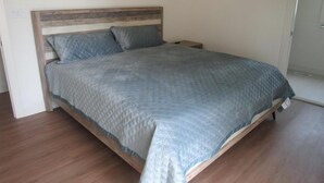Ein Einzelbett mit Holz-Kopfteil, einer grauen gesteppten Bettdecke und zwei Kissen.