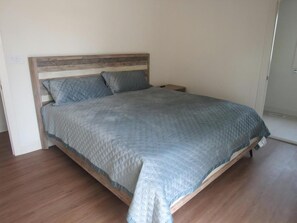 A single bed with a wooden headboard, a grey quilted bedspread, and two pillows. - STEPS TO OCEAN 6 Bedroom House w / elevator (Harvey Cedars)