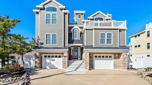 A two-story house with a stone foundation, a front porch, and a garage.
