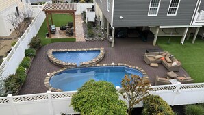 A backyard with a swimming pool, patio furniture, and a pergola.