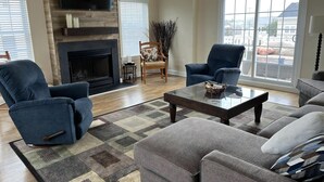 A spacious living room with a fireplace, a large window, and a modern TV.
