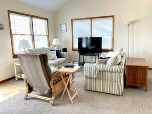 A living room with a television, two sofas, a coffee table, and a lamp.