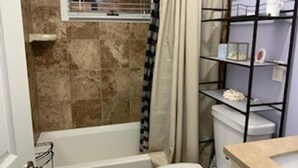 A bathroom with a bathtub, toilet, and shelves with toiletries. - Short walk to Ocean-great for large family (Beach Haven Terrace)