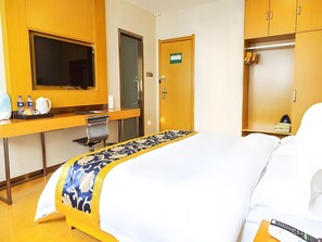 Ein Hotelzimmer mit einem Bett, einem Schreibtisch mit Stuhl, einem Fernseher und einem Kleiderschrank.