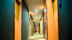 A hotel hallway with a carpeted floor, wooden doors, and a sign indicating the direction to the elevator. - Greentree Inn Xi an Ming City Wall Northwest Dafengqing Road Business Hotel (Xi'an)