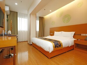 Ein modernes Hotelzimmer mit einem großen Bett, Holzboden und einem Schreibtisch mit Spiegel.