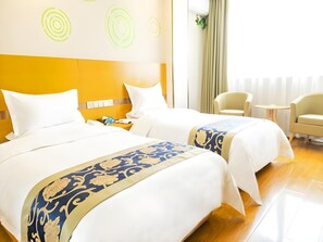 Ein Hotelzimmer mit zwei Betten, einem kleinen Tisch und zwei Stühlen.