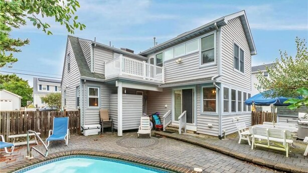 Une maison à deux étages avec une piscine, un patio couvert et une cour arrière clôturée.