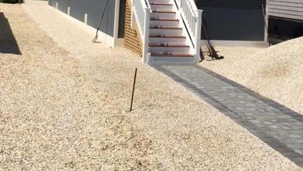 Ein zweistöckiges Haus mit einer Veranda und einer Treppe, die zum Eingang führt.