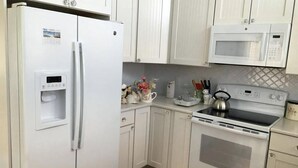 Eine Küche mit Kühlschrank, Mikrowelle, Herd und Wasserspender.
