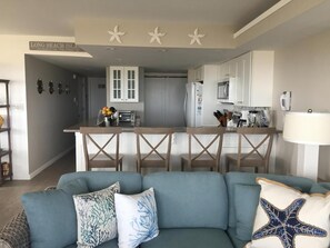 A modern kitchen with white cabinets, a central island, and a bar area.