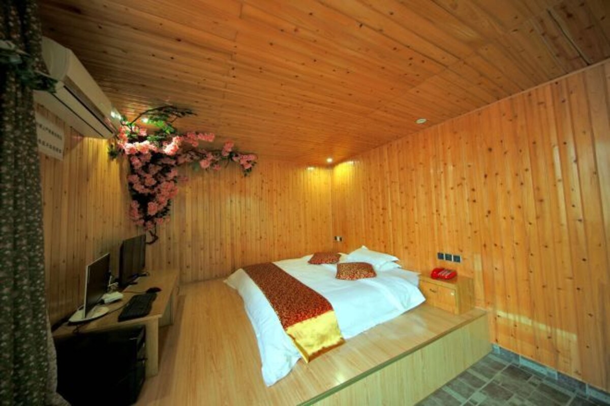 A wooden-paneled room with a bed, a desk, and a small cabinet.