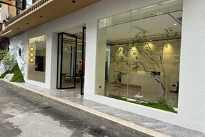 A modern building with large glass windows, a visible entrance, and a small indoor garden. - Yin E Hotel (Emeishan City)
