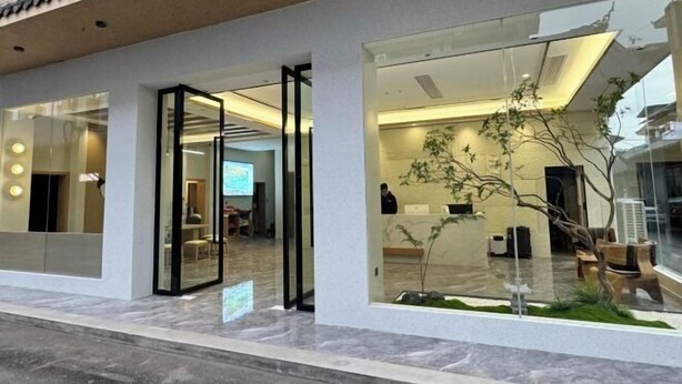 A modern hotel lobby with a glass entrance, a reception desk, and a small indoor garden. - Yin E Hotel (Emeishan City)