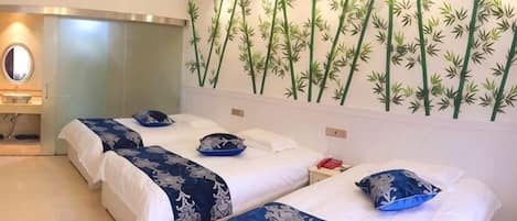 A hotel room with two beds, a mirror, and a wall with bamboo wallpaper.