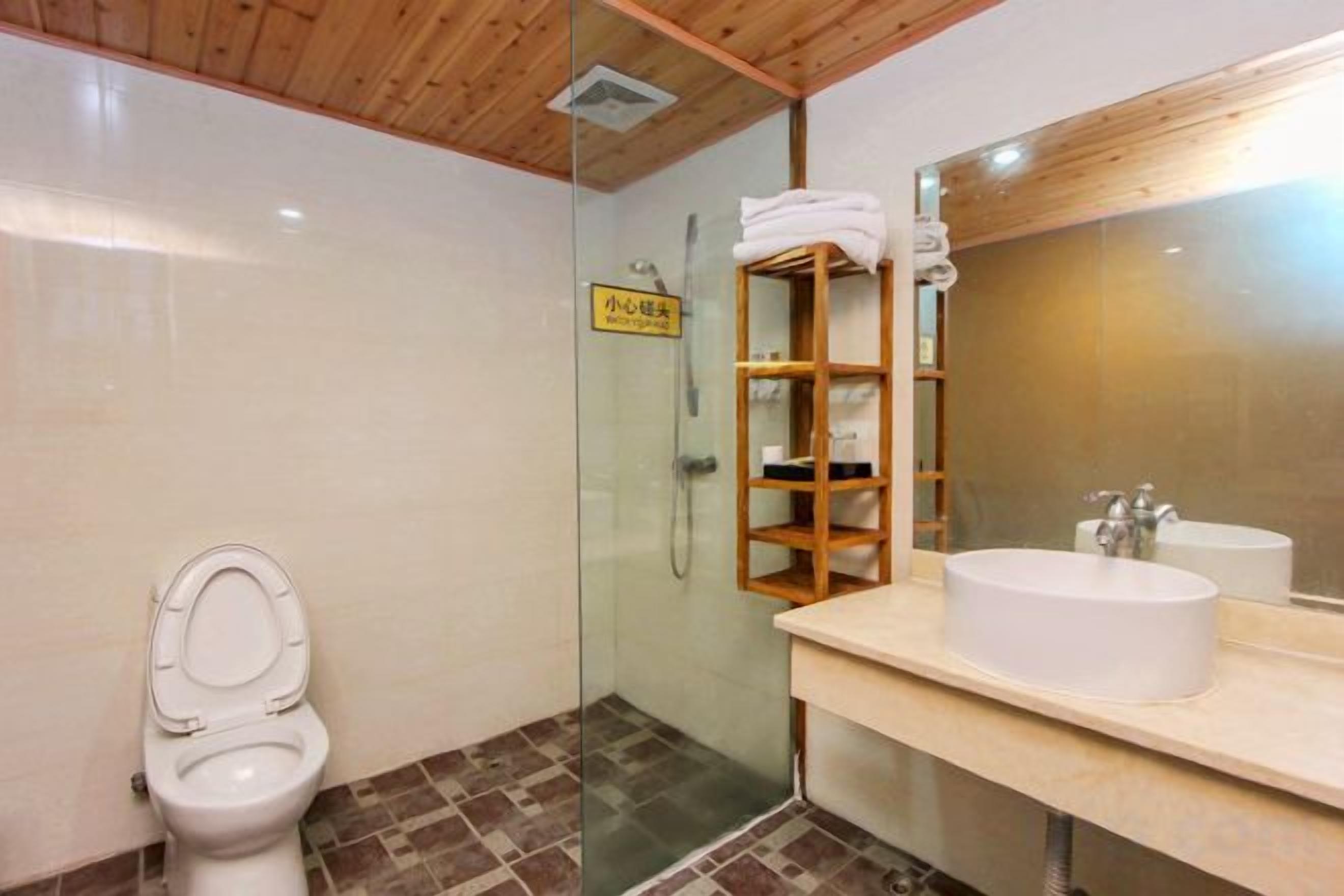 A bathroom with a toilet, a glass-enclosed shower, a sink with a mirror, and a towel rack.