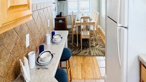 A compact kitchen with wooden cabinets, a white refrigerator, and a dining area with a table and chairs.