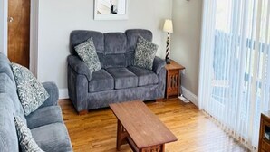 A living room with a grey sofa set, a wooden coffee table, and a wooden floor.