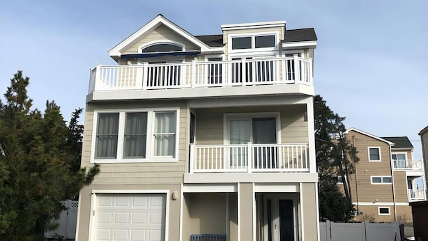 A two-story residential building with a garage, a balcony on the upper floor, and a driveway leading to the entrance.
