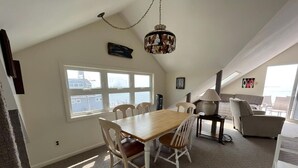 A dining area with a wooden table and chairs, a chandelier, and a view of the city through large windows.