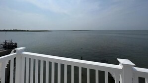 A view from a balcony overlooking a calm body of water with a distant shoreline.