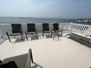 A deck with outdoor seating and a view of the sea. - Classic beach house on the bay (Beach Haven Gardens)