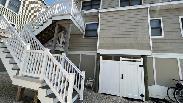 A multi-story residential building with a central staircase, a gated entrance, and a bicycle parked outside.