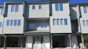 A multi-story residential building with a covered front porch, a bicycle parked outside, and a small garden area. - Nice townhouse style condo with pool in Brant Beach. Unit overlooks pool and. (Brant Beach)