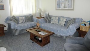 A living room with a sofa set, a coffee table, a lamp, and a framed picture on the wall. - Nice townhouse style condo with pool in Brant Beach. Unit overlooks pool and. (Brant Beach)