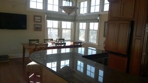 A spacious kitchen with a large island, wooden cabinets, and large windows providing natural light.