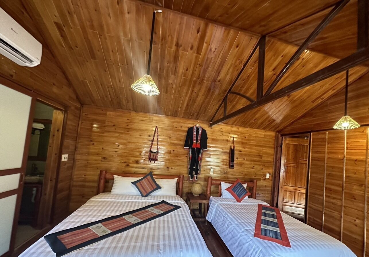A wooden cabin-style room with two beds, a hanging light fixture, and a wardrobe.