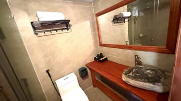 A bathroom with a toilet, sink, mirror, towel rack, and shower area.