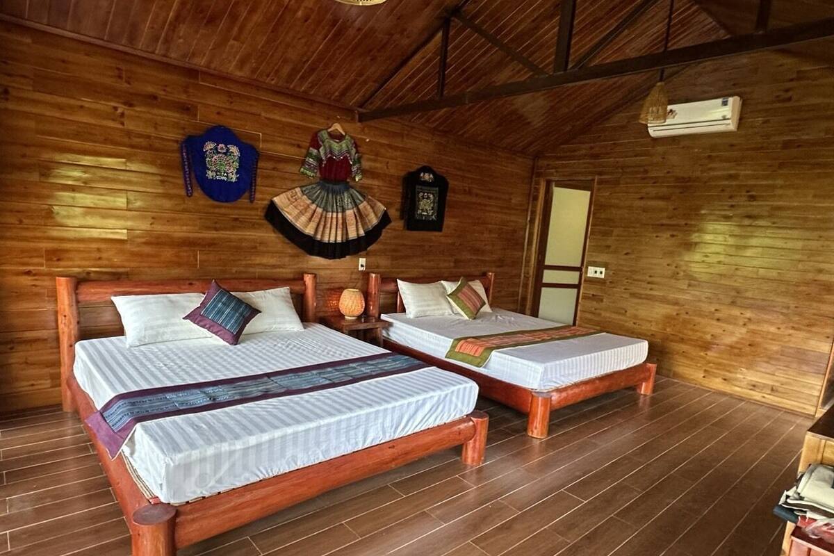 A wooden room with two beds, a wooden ceiling, and a door.