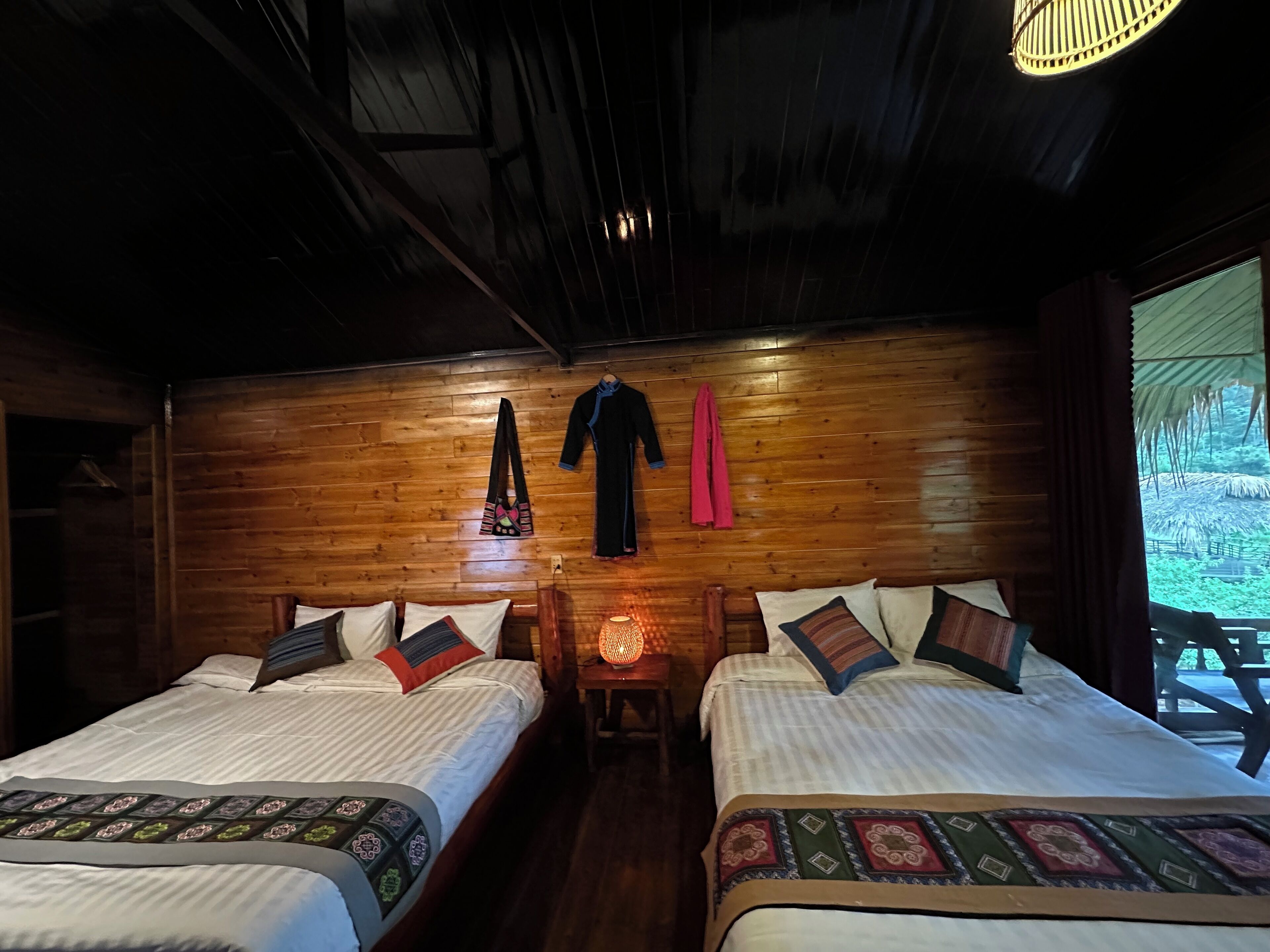 A wooden room with two beds, a hanging garment rack, and a nightlight.