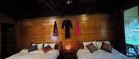 A wooden room with two beds, a hanging garment rack, and a nightlight.