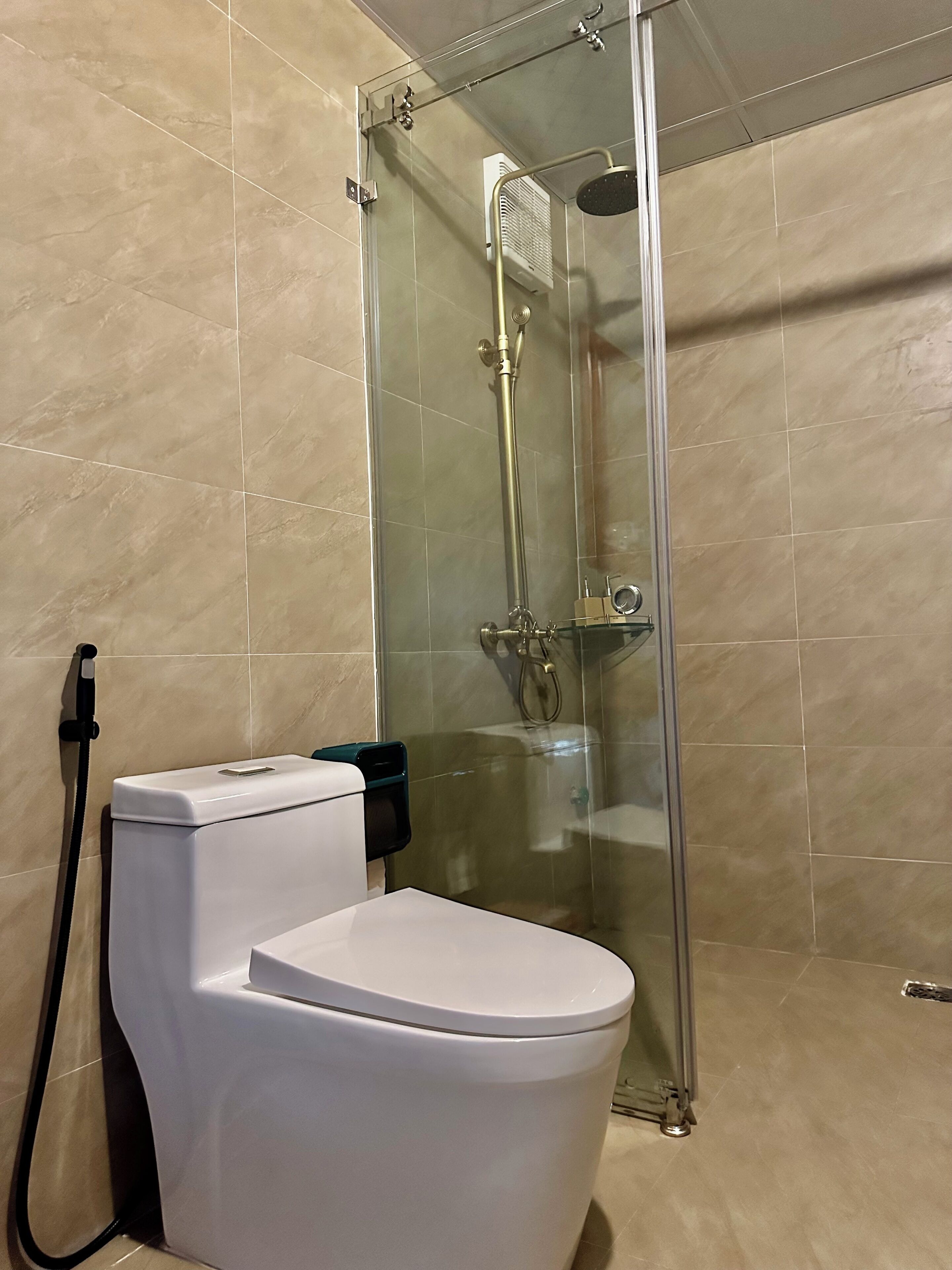 Et moderne badeværelse med bruseniche, et hvidt toilet og et håndklædet ørrestativ.