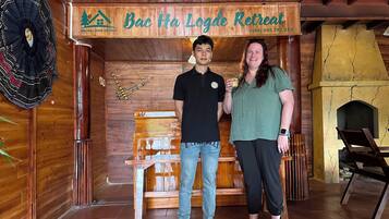 A wooden interior with a sign reading "Bac Ha Logde Retreat" and a contact number.