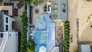 Vista aérea de una zona residencial con un patio azul con diseño, un espacio de estar circular y un pequeño jardín.