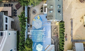 Vista aérea de uma área residencial com um pátio azul estampado, uma área de estar circular e um pequeno jardim.