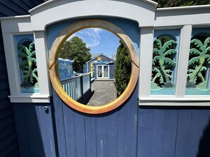 A circular window with a view of a building with a blue roof and white trim.