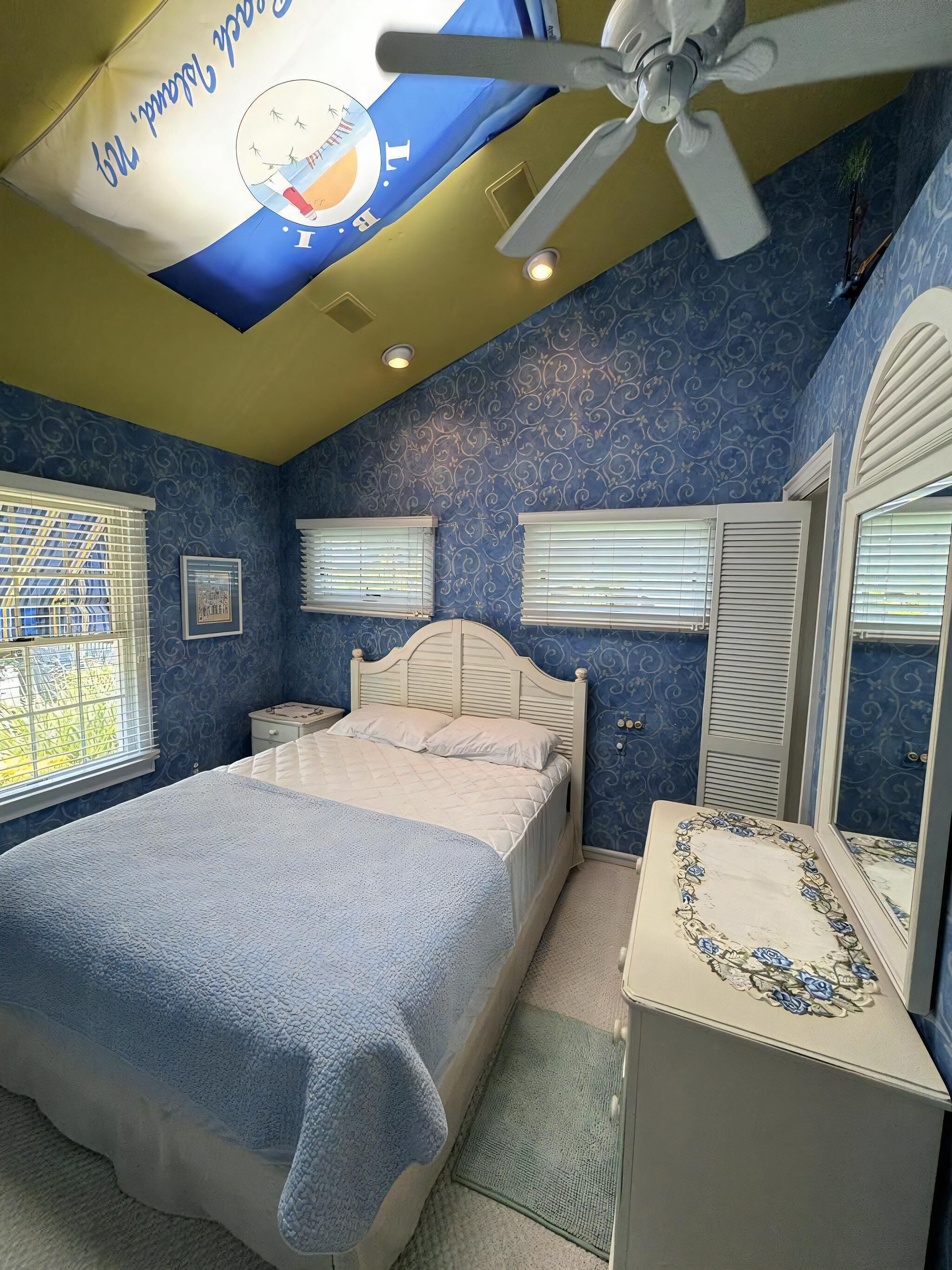 A bedroom with a bed, nightstands, a ceiling fan, and a window with blinds.