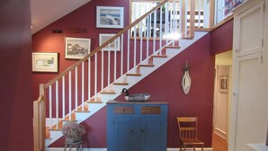 Eine Treppe mit weißen Geländern, einem blauen Schrank, einem Holzstuhl und einem Teppich mit Meeresmotiven.