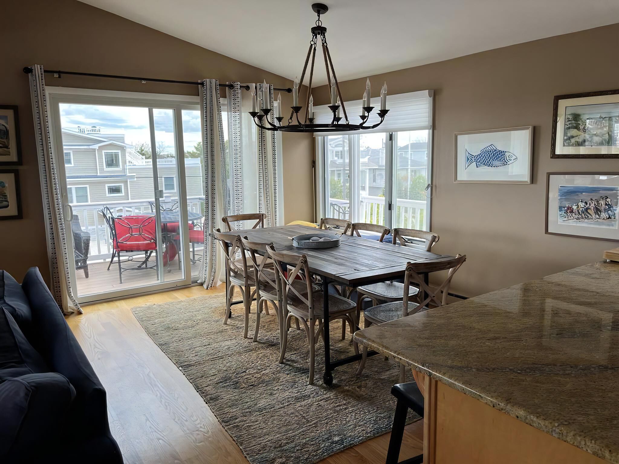 A dining area with a table and chairs, a chandelier, and a view through glass doors to the outside.
