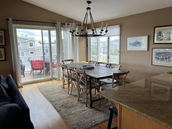 A dining area with a table and chairs, a chandelier, and a view through glass doors to the outside.