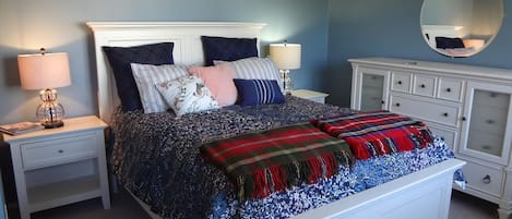 A bedroom with a bed, nightstands, a dresser, and a mirror.